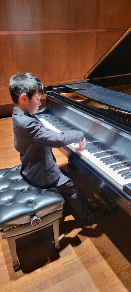 CAM student taking piano lessons in Issaquah shows range of wrist motion on one of Benaroya Hall's concert Steinway model D's.